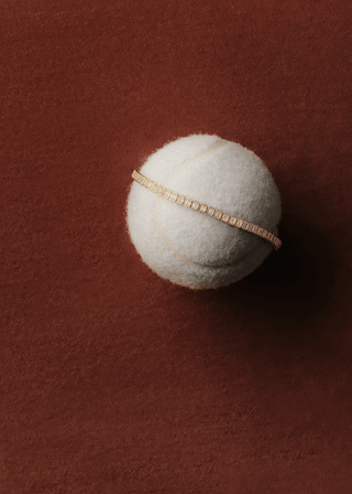 Emerald cut bezel lab grown diamond bracelet resting on a tennis ball, showcasing elegant design and craftsmanship.